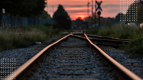 Metal train tracks in rural area at sunset