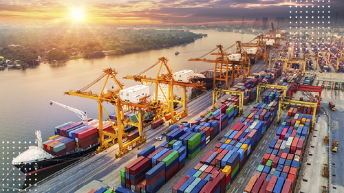 Cargo containers at port near docked vessel at sunset