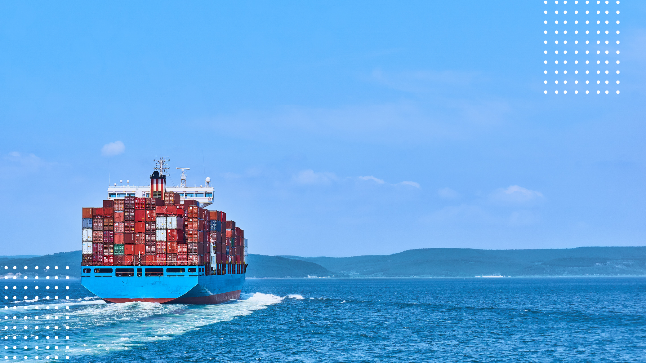 Colorful containers on container ship in the ocean moving towards moutains